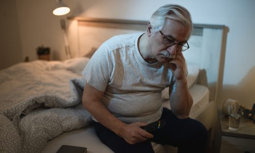 Sleepless mature man contemplating while sitting on the ned at night.